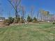 Spacious backyard with lush green lawn, mature trees, and landscaping creating a serene outdoor space at 7240 Baybrooke Ln, Harrisburg, NC 28075