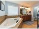 Clean bathroom featuring a garden tub, double vanity with granite countertops, and a large window at 7240 Baybrooke Ln, Harrisburg, NC 28075