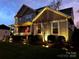 Charming home with a welcoming front porch, American flag, and professional landscape lighting at 7240 Baybrooke Ln, Harrisburg, NC 28075