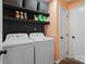 Functional laundry room with washer, dryer, storage shelves, and hardwood floors at 7656 Eastbourne Rd, Charlotte, NC 28227