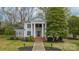Classic white home boasts grand columns, a brick staircase, and lush greenery in the front yard at 8425 E Franklin St, Mount Pleasant, NC 28124