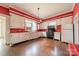 Vintage kitchen with bright red walls, white cabinetry, hardwood floors, and an antique stove as its centerpiece at 8425 E Franklin St, Mount Pleasant, NC 28124