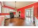 Vintage kitchen showcasing bright red walls, white cabinetry, hardwood floors, and a classic stove at 8425 E Franklin St, Mount Pleasant, NC 28124