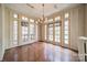 Bright sunroom bathed in natural light from numerous windows, showcasing hardwood floors and a vintage chandelier at 8425 E Franklin St, Mount Pleasant, NC 28124