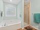 Bright bathroom showcasing tub, glass block window, and tiled shower at 8801 Oldenburg Dr, Mount Pleasant, NC 28124