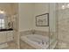 Elegant bathroom featuring a soaking tub, tiled walls, and natural light at 9703 Cotton Stand Rd, Charlotte, NC 28277