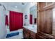 Well-lit bathroom features a shower with red curtain, single vanity, and ample storage space at 1027 Brookline Dr, Huntersville, NC 28078