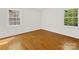 Well-lit bedroom showcasing gleaming hardwood floors and natural light from two windows at 5114 Glenbrier Dr, Charlotte, NC 28212