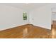 Sunlit bedroom showing hardwood floors, neutral walls, and window overlooking trees at 5114 Glenbrier Dr, Charlotte, NC 28212