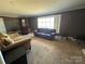 A living room features a large window, a brown sofa and dated carpeting at 5226 Indian Trail Fairview Rd, Indian Trail, NC 28079