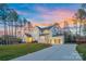 Stunning two-story home with a three-car garage, lush green lawn, and a beautifully colored sky at dusk at 6398 Chimney Bluff Rd, Lancaster, SC 29720