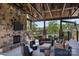 Inviting covered patio featuring a stone fireplace, TV, comfortable seating, and views of the surrounding greenery at 6398 Chimney Bluff Rd, Lancaster, SC 29720