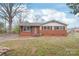 Charming single-story brick home with black shutters, a classic gable roof, and a well-manicured lawn under a blue sky at 7207 Idlewild Rd, Charlotte, NC 28212