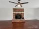 Cozy living room with a brick fireplace, hardwood floors, and a modern ceiling fan at 11712 Battery Pl, Charlotte, NC 28273