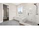 Bathroom featuring a tub, glass enclosed shower with marble tile, and herringbone tile floors at 2017 Belle Grove Dr, Waxhaw, NC 28173