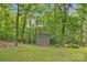 Backyard view of a storage shed surrounded by trees and an iron fence at 298 Poplar Grove Ct, Taylorsville, NC 28681