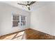 Bright bedroom with hardwood floors, ceiling fan, and a large window overlooking the neighborhood at 415 Spring St, Davidson, NC 28036