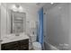 Bathroom features a shower-tub combo with blue curtains, a mirror, and a white sink with dark wooden cabinets at 6004 Clover Hill Rd, Indian Trail, NC 28079