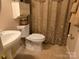 Cozy bathroom featuring a sink, toilet, and shower with patterned curtain and storage at 8411 Rhian Brook Ln, Charlotte, NC 28216