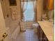 Well-lit bathroom featuring a bathtub, tiled floors, vanity, and window with decorative curtains at 8411 Rhian Brook Ln, Charlotte, NC 28216