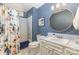 Stylish blue bathroom with patterned wallpaper, round mirror, and shower-tub combination at 3004 Vernell Ln, Shelby, NC 28150