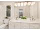 Bright bathroom featuring double sinks, white cabinetry, and large vanity mirror at 10602 Country Squire Ct, Matthews, NC 28105
