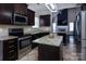 Modern kitchen with stainless steel appliances, granite countertops, dark cabinets, and an adjacent living room at 10928 Jardin Way, Charlotte, NC 28215