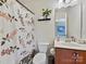 This bathroom features a floral shower curtain, a toilet, and a vanity with storage at 11621 Red Knoll Ln, Pineville, NC 28134