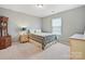 This bedroom has neutral walls with a bed with patterned bedding, and wooden furniture at 11621 Red Knoll Ln, Pineville, NC 28134