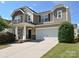 Attractive two-story home with a two-car garage, stone accents, and a well-maintained front lawn on a sunny day at 11621 Red Knoll Ln, Pineville, NC 28134