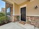 Close-up of front door with stone and beige siding and black shutters on the windows at 11621 Red Knoll Ln, Pineville, NC 28134