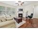 Bright living room with hardwood floors, fireplace, a ceiling fan, and large windows for natural light at 11621 Red Knoll Ln, Pineville, NC 28134