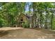 Inviting lake house featuring beautiful wood siding, mature trees, and picturesque waterfront views at 121 Rhinehill Dr, Mooresville, NC 28117