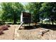 Wooden play set with a slide and climbing area, nestled among mature trees in the backyard at 1300 Aragon Beach Rd, Rock Hill, SC 29732
