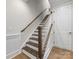 Staircase featuring hardwood steps, white risers, wood handrail, and a white paneled door at 1413 Kenilworth Ave, Charlotte, NC 28203