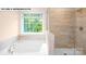 Bright bathroom featuring a soaking tub and a separate glass-enclosed shower at 134 Asmodean Ln, Troutman, NC 28166