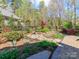 Wide angle of fenced backyard with landscaped garden, water fountain, stone patio, and bordered with mature trees at 2342 Wesley Landing Rd, Waxhaw, NC 28173