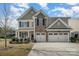 Inviting two-story home featuring a stone facade and a spacious three-car garage and manicured lawn at 276 Annatto Way, Tega Cay, SC 29708