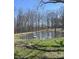 Picturesque view of a serene pond reflecting the surrounding trees on a clear, sunny day at 3225 Liberty Rd, Gold Hill, NC 28071