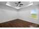 Bright bedroom with hardwood floors, a tray ceiling with fan, and a window overlooking a field at 3907 E Lawyers Rd, Monroe, NC 28110