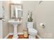 Charming powder room with pedestal sink, decorative mirror, and neutral color scheme at 4205 New Town Rd, Waxhaw, NC 28173