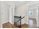 Hallway with hardwood floors, white walls, dark brown bannister and handrail, and a view into an adjacent bedroom at 4601 Crooked Oak Ln, Charlotte, NC 28226
