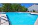 Bright blue community pool with safety markers and many lounge chairs, set against lush green trees and clear, cloudless sky at 7869 Iron Rd, Sherrills Ford, NC 28673
