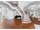 Elegant foyer featuring a grand staircase with iron railings and hardwood floors, complemented by a black piano at 8228 Bay Pointe Dr, Denver, NC 28037