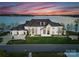 Stately white brick home with a well-manicured lawn, elegant landscaping, and circular driveway at sunset at 8228 Bay Pointe Dr, Denver, NC 28037