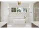 Bright bathroom boasts a soaking tub beneath a large window, flanked by sconces at 8813 Graham Rd, Denver, NC 28037