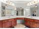 A large bathroom boasts dual sinks, wood cabinets and an expansive three-section mirror at 9113 Cinder Ln, Huntersville, NC 28078