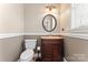 Cozy half bathroom featuring a vanity sink, toilet, and wainscotting at 9113 Cinder Ln, Huntersville, NC 28078
