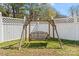 Charming wooden yard swing offers a relaxing spot surrounded by green grass and white fencing at 9113 Cinder Ln, Huntersville, NC 28078
