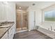 A modern bathroom with a soaking tub, stand up shower, and gray wood-look floors at 9937 Travertine Trl, Davidson, NC 28036